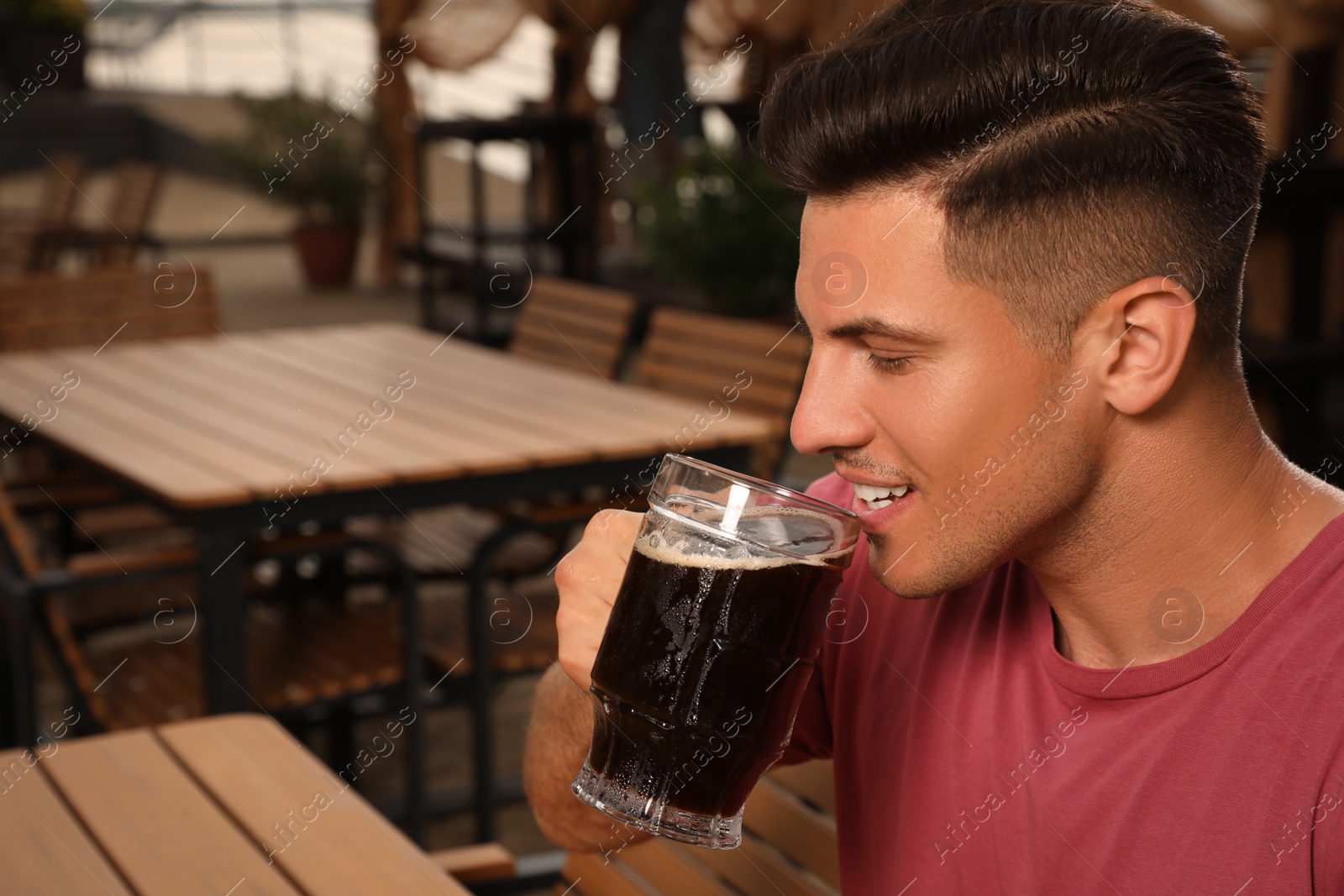 Photo of Man drinking dark beer in outdoor cafe, space for text