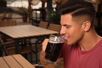 Photo of Man drinking dark beer in outdoor cafe, space for text