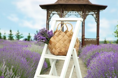 Photo of Wicker bag with beautiful lavender flowers outdoors