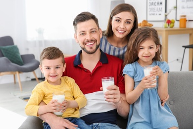 Photo of Happy family with glasses of milk in living room