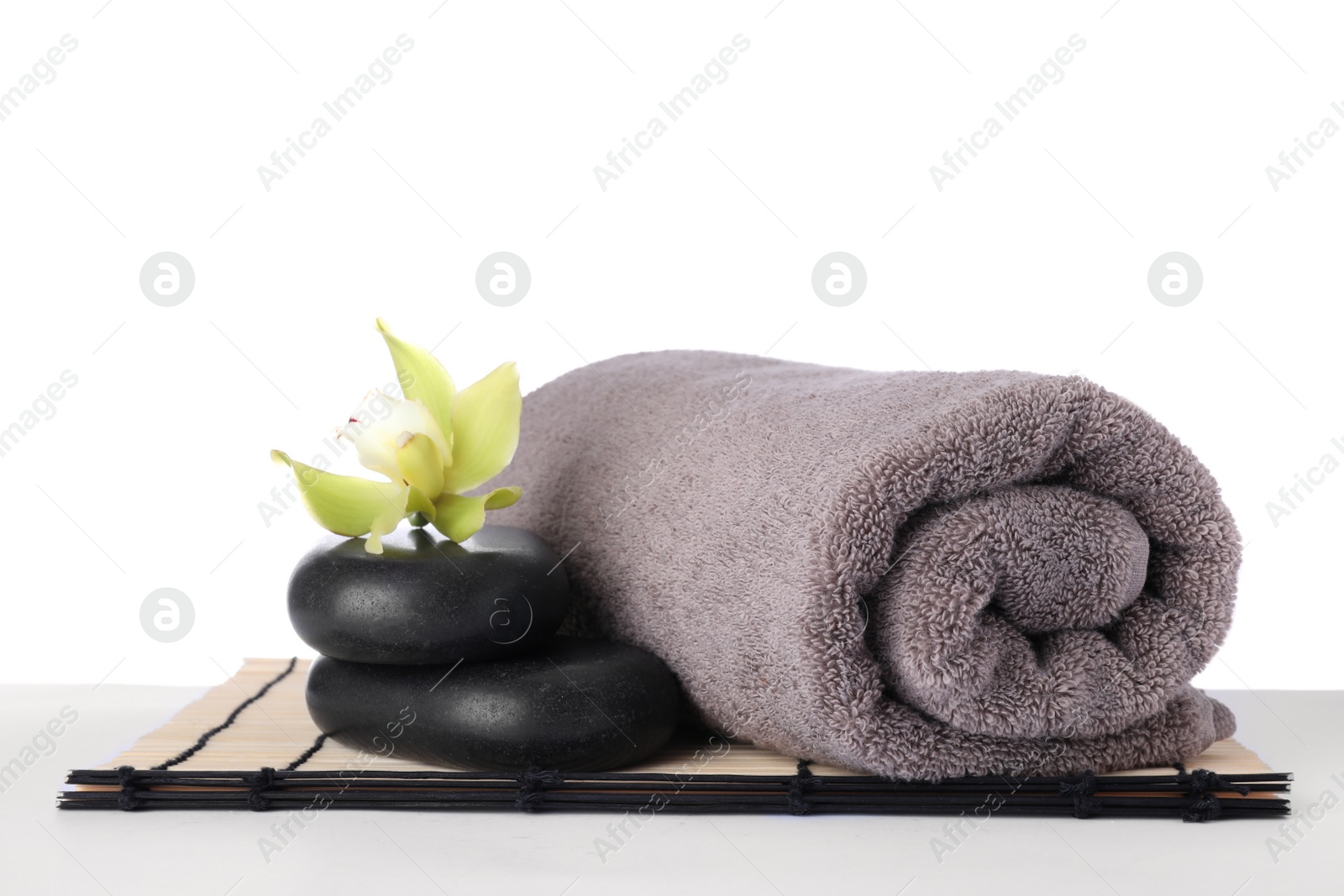 Photo of Mat with towel, spa stones and exotic flower isolated on white