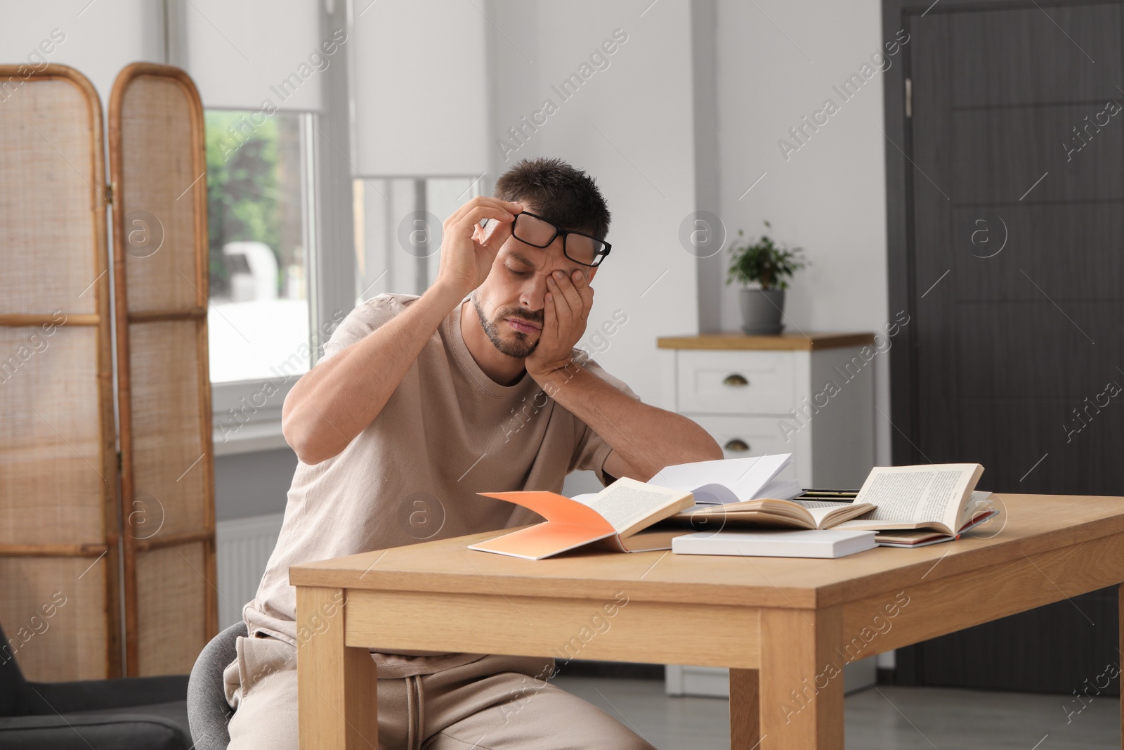 Photo of Sleepy man studying at wooden table indoors