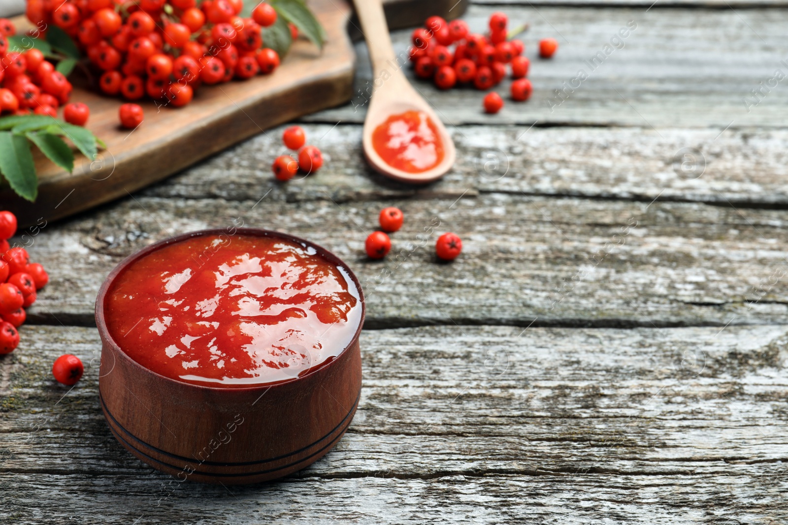 Photo of Delicious rowan jam in bowl on wooden table. Space for text