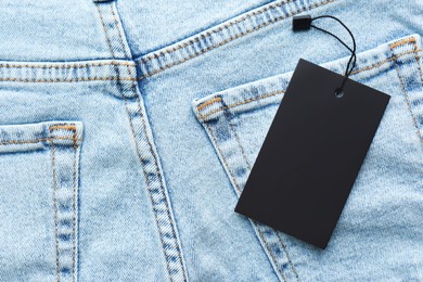 Photo of Blank tag on jeans, top view. Space for text