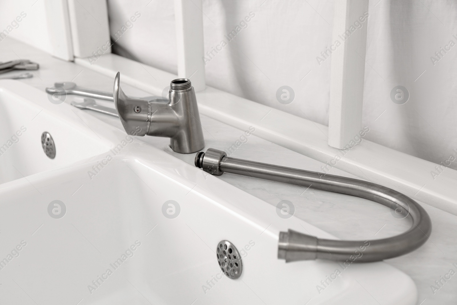 Photo of Plumber's tools and water tap ready for installation near sink on countertop in kitchen