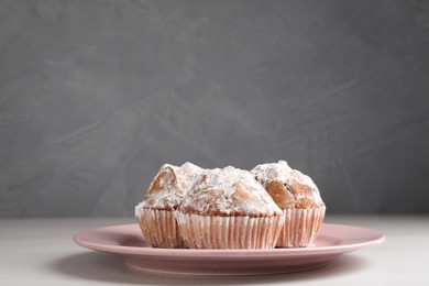 Photo of Tasty muffins with sugar powder on white wooden table, closeup