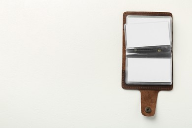 Photo of Leather business card holder with blank cards on white table, top view. Space for text