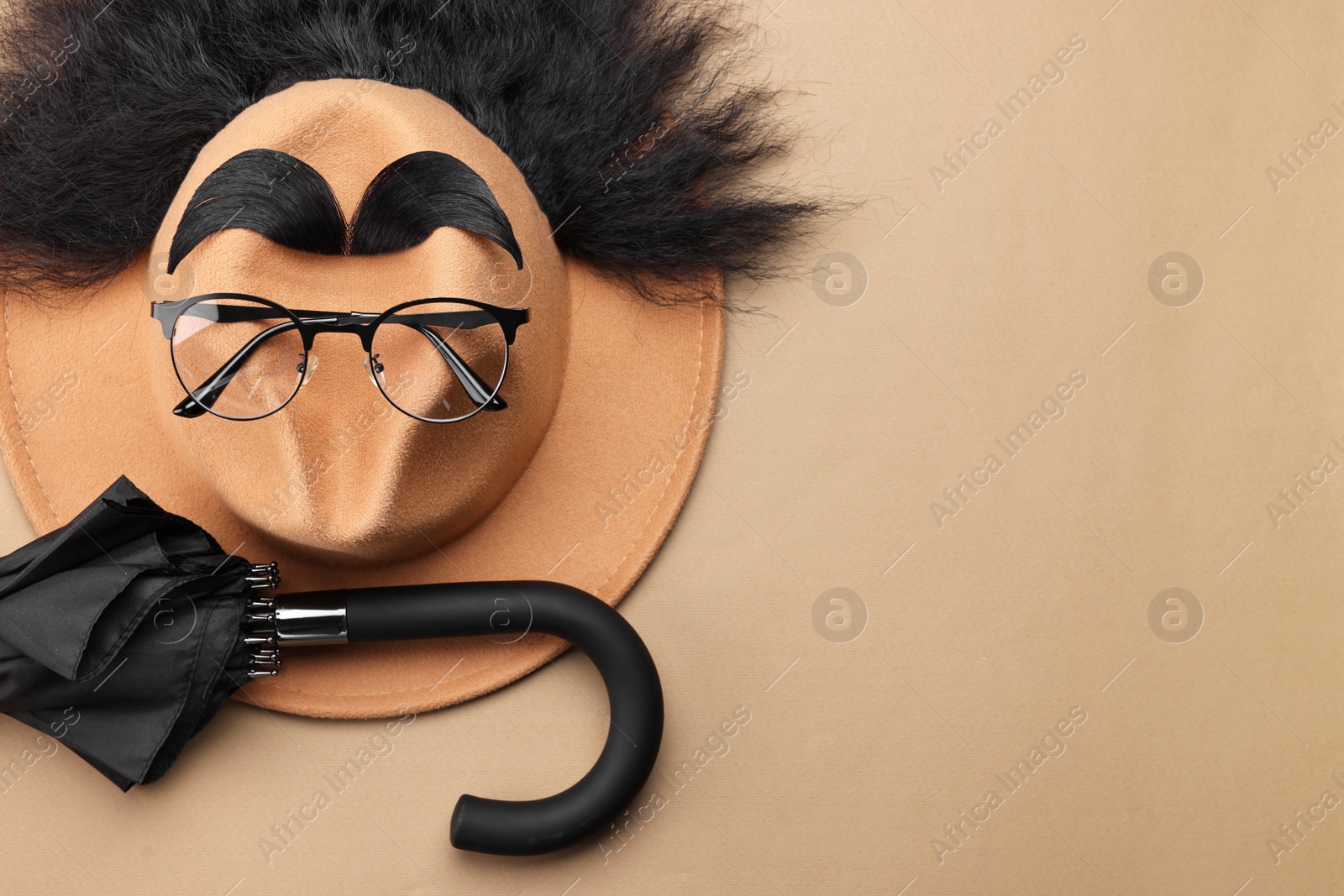 Photo of Man's face made of artificial hair, eyebrows, glasses and hat on beige background, top view. Space for text