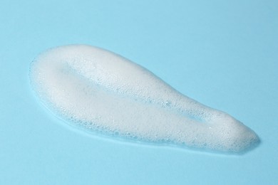 Photo of Foam on light blue background. Face cleanser, skin care cosmetic
