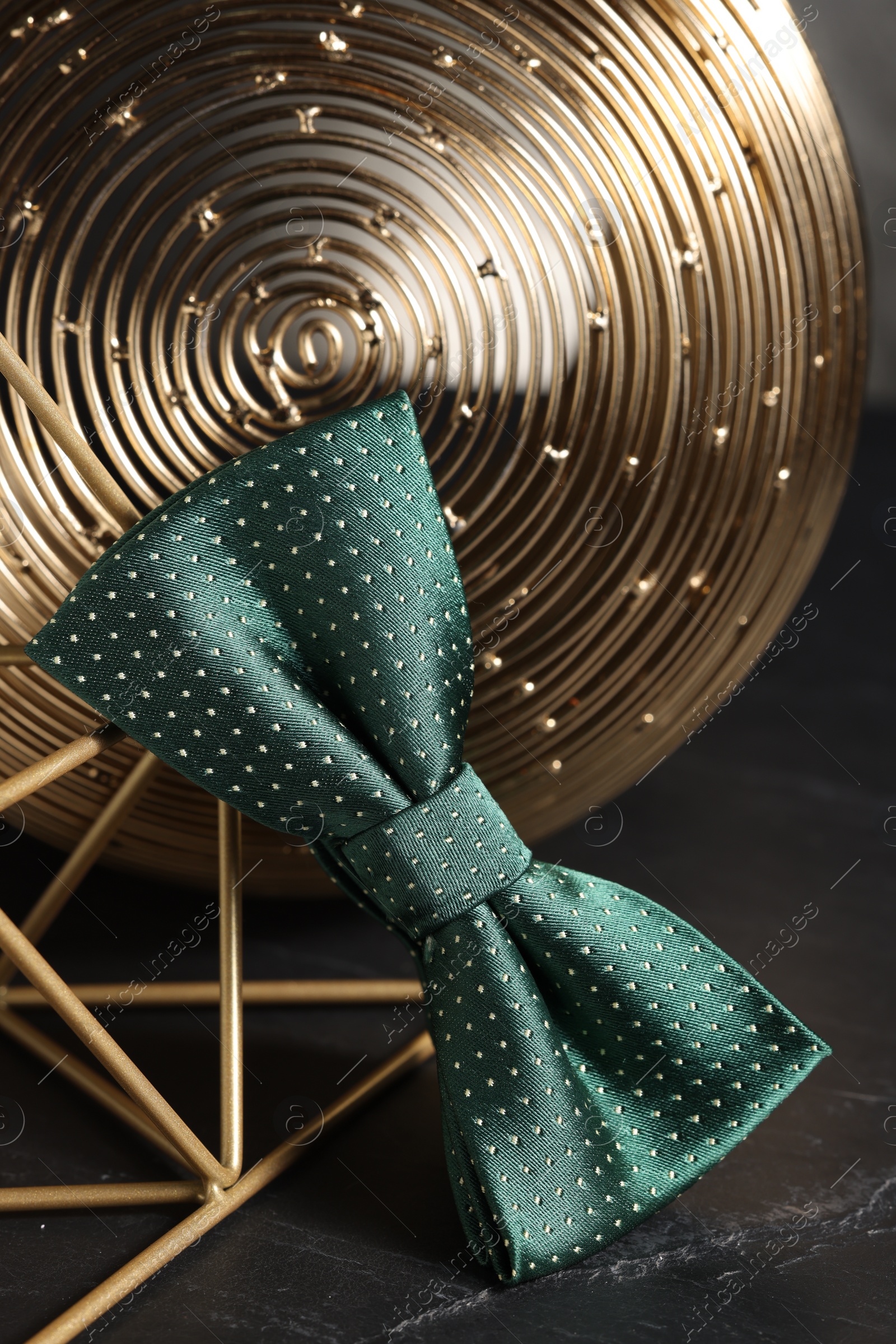 Photo of Stylish presentation of green bow tie on black table