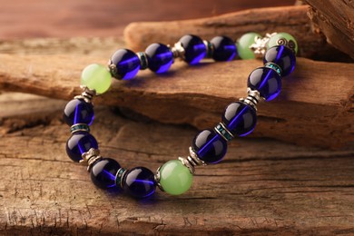 Photo of Stylish presentation of beautiful bracelet with gemstones on wooden table, closeup