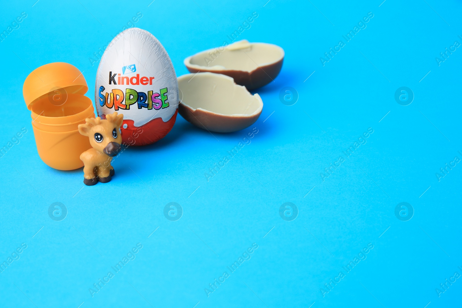 Photo of Slynchev Bryag, Bulgaria - May 25, 2023: Kinder Surprise Eggs, plastic capsule and toy deer on light blue background, space for text