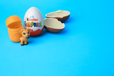 Photo of Slynchev Bryag, Bulgaria - May 25, 2023: Kinder Surprise Eggs, plastic capsule and toy deer on light blue background, space for text