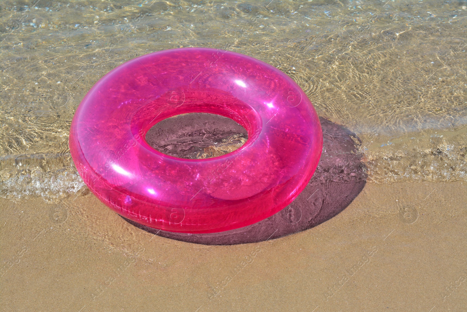 Photo of Bright inflatable ring on sandy beach near sea