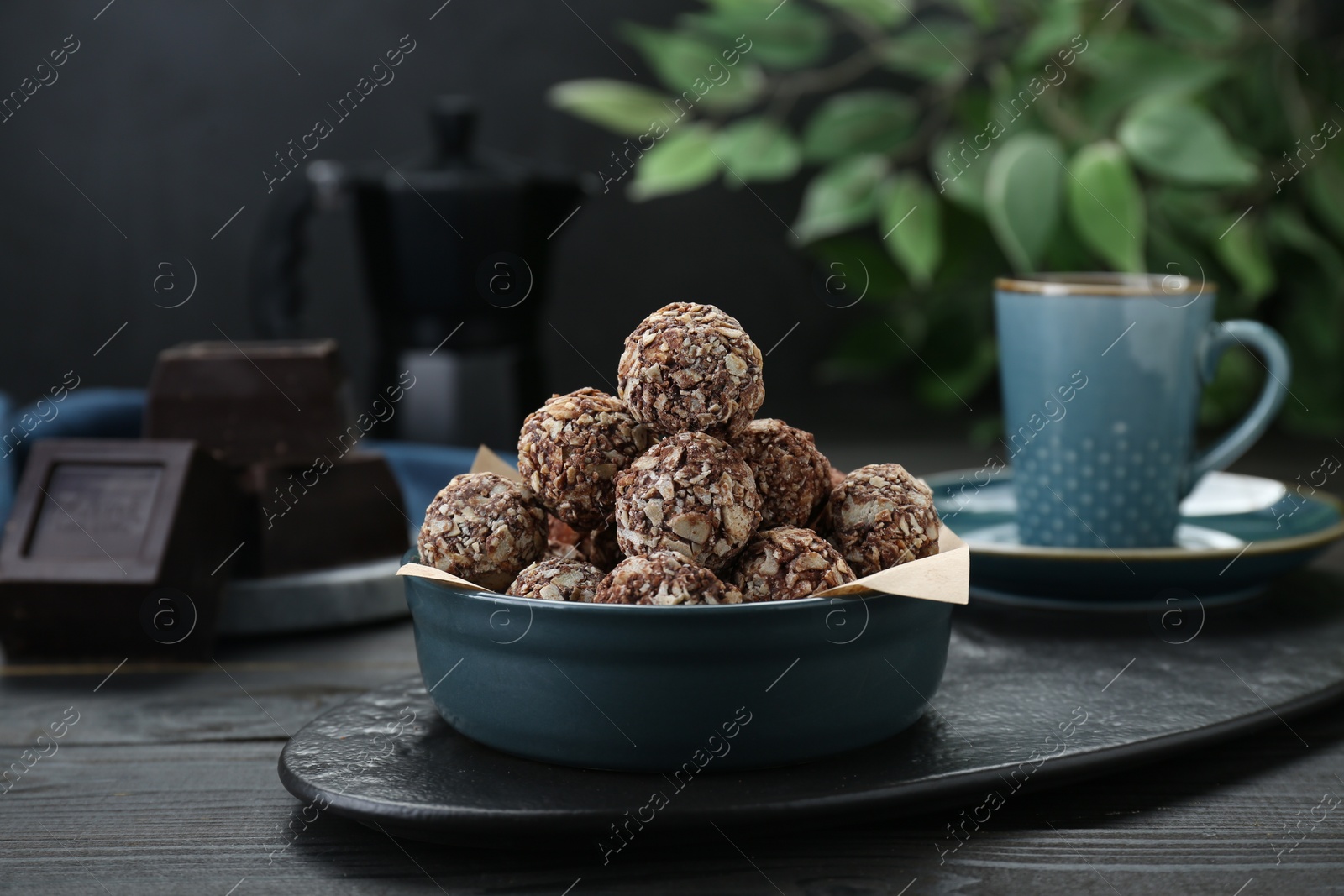 Photo of Bowl of delicious sweet chocolate candies on black wooden table