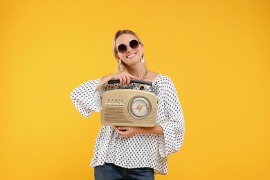 Portrait of happy hippie woman with retro radio receiver on yellow background