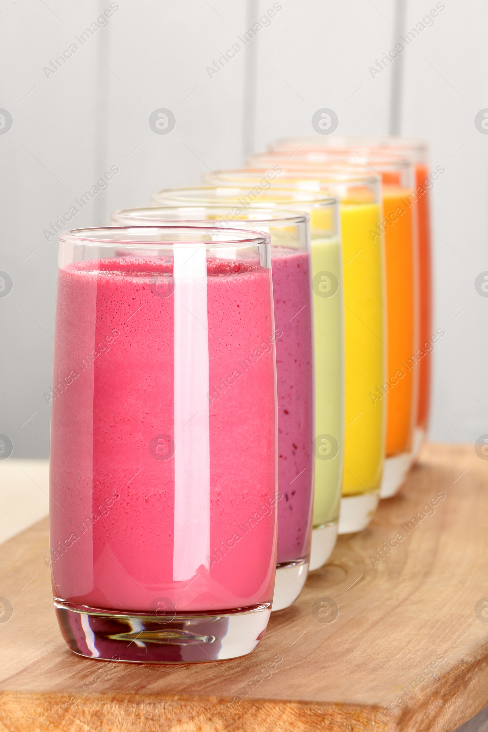 Photo of Many different tasty smoothies on wooden board