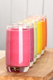 Photo of Many different tasty smoothies on wooden board