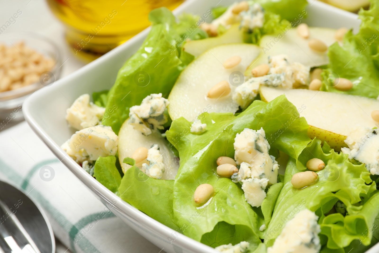 Photo of Fresh salad with pear slices in bowl, closeup