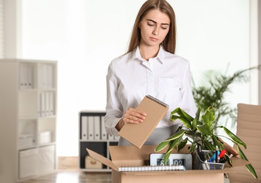 Upset young woman packing stuff in box at office