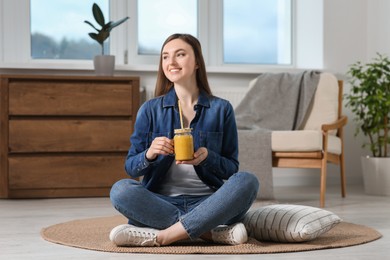 Beautiful young woman with delicious smoothie on floor at home
