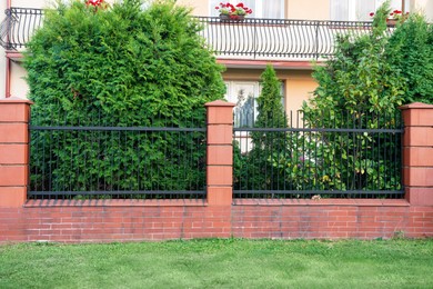 Photo of Beautiful brick fence with iron railing outdoors