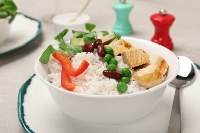 Photo of Bowl of boiled rice with vegetables and meat on table