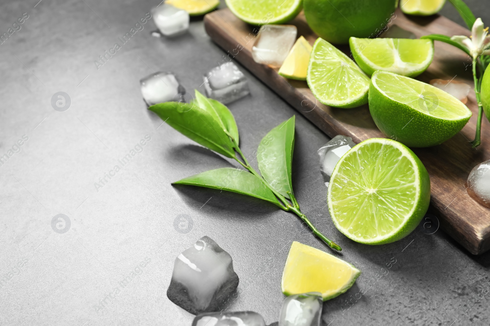 Photo of Composition with fresh ripe limes and ice cubes on gray background