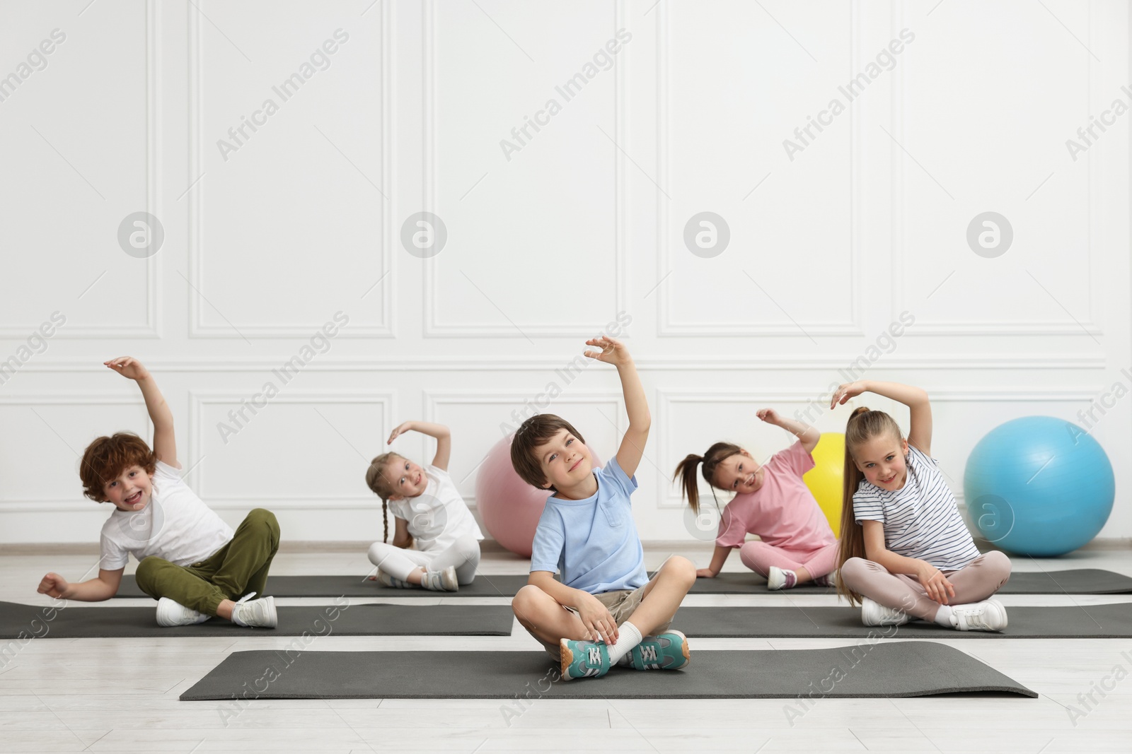 Photo of Group of children doing gymnastic exercises on mats indoors