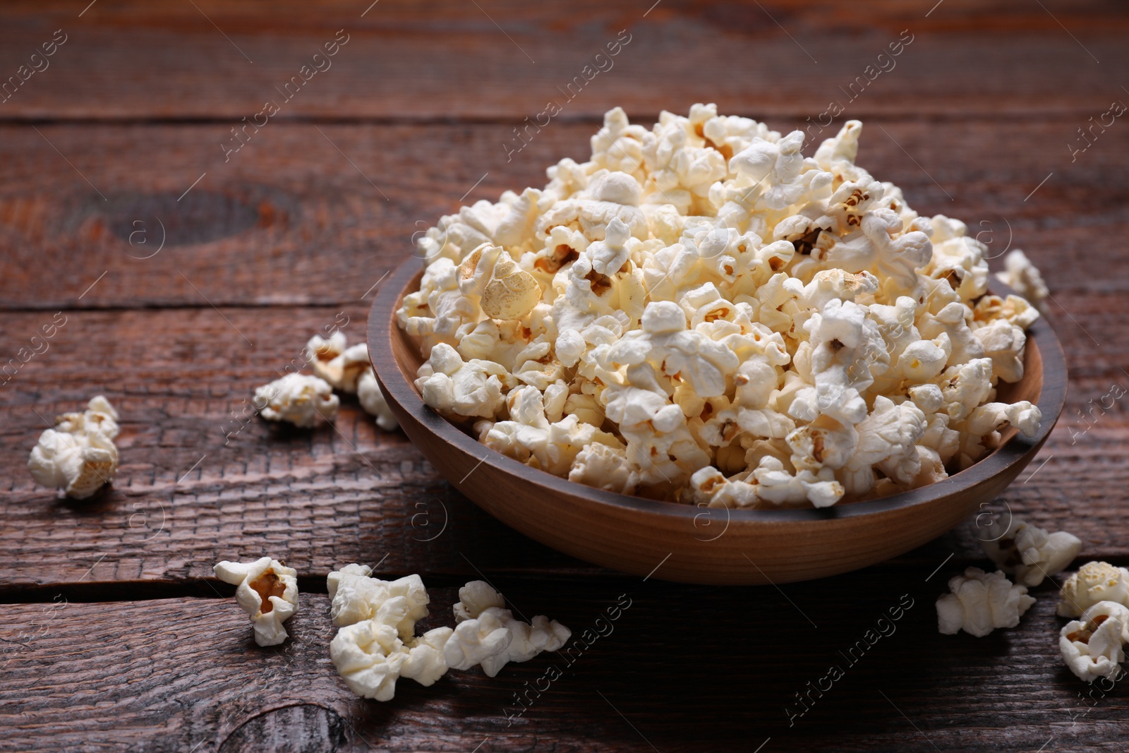 Photo of Bowl of tasty popcorn on wooden table, space for text