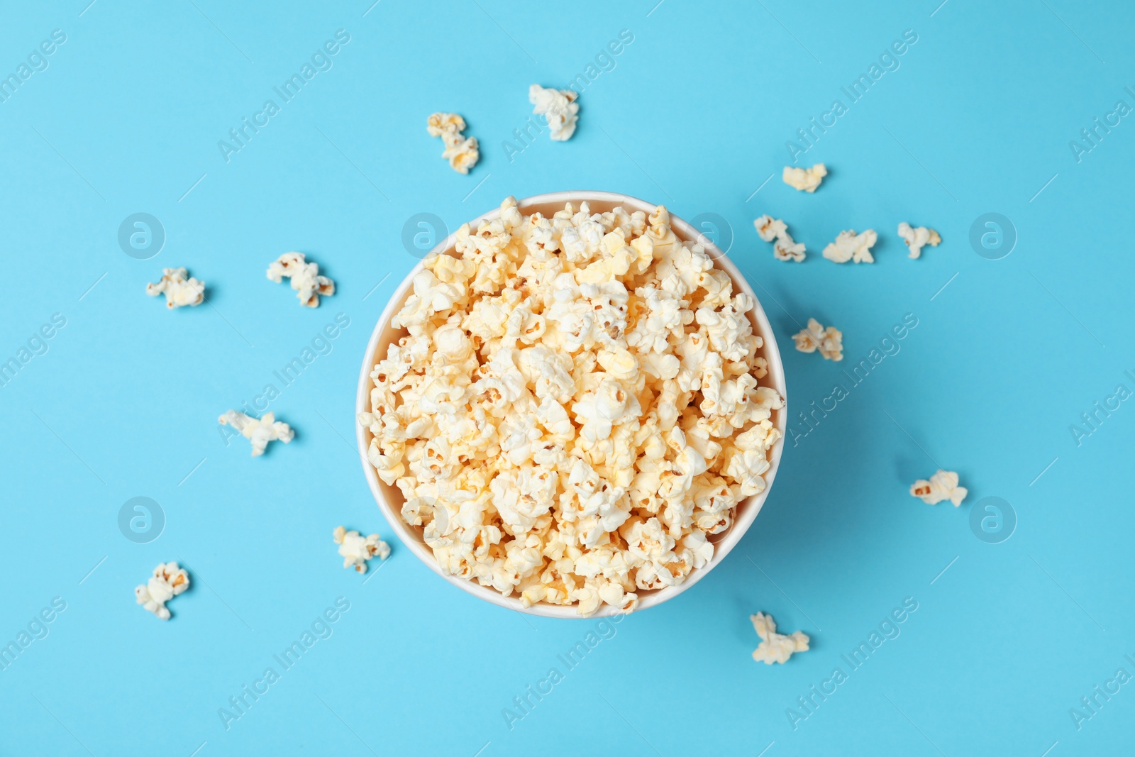 Photo of Paper cup with tasty popcorn on color background, top view