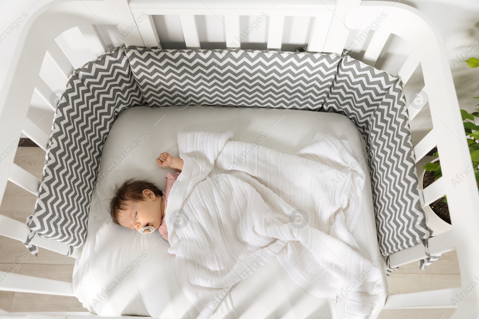 Photo of Cute little baby sleeping in cosy crib indoors