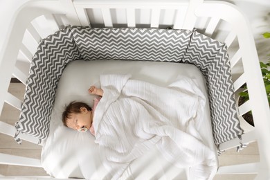 Cute little baby sleeping in cosy crib indoors