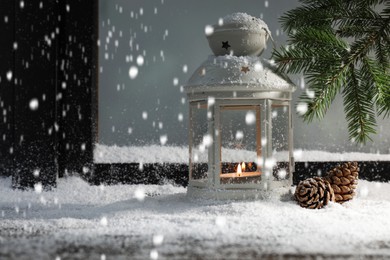 Photo of Snow falling onto window sill with Christmas lantern, outdoors. Space for text