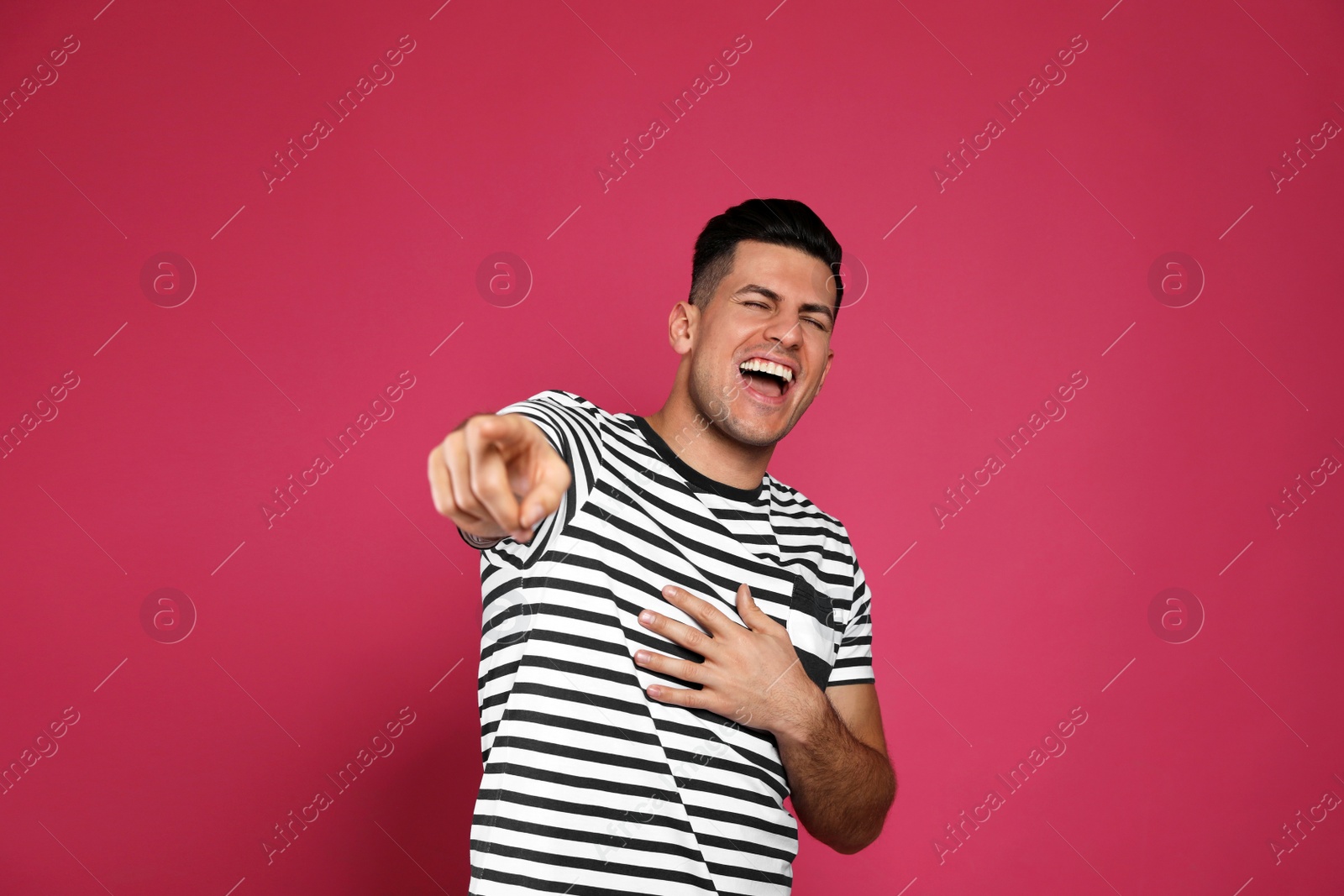 Photo of Handsome man laughing on maroon background. Funny joke