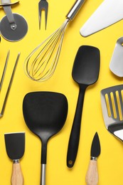 Photo of Different spatulas and other kitchen utensils on yellow background, flat lay