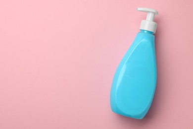Bottle of liquid soap on pink background, top view. Space for text
