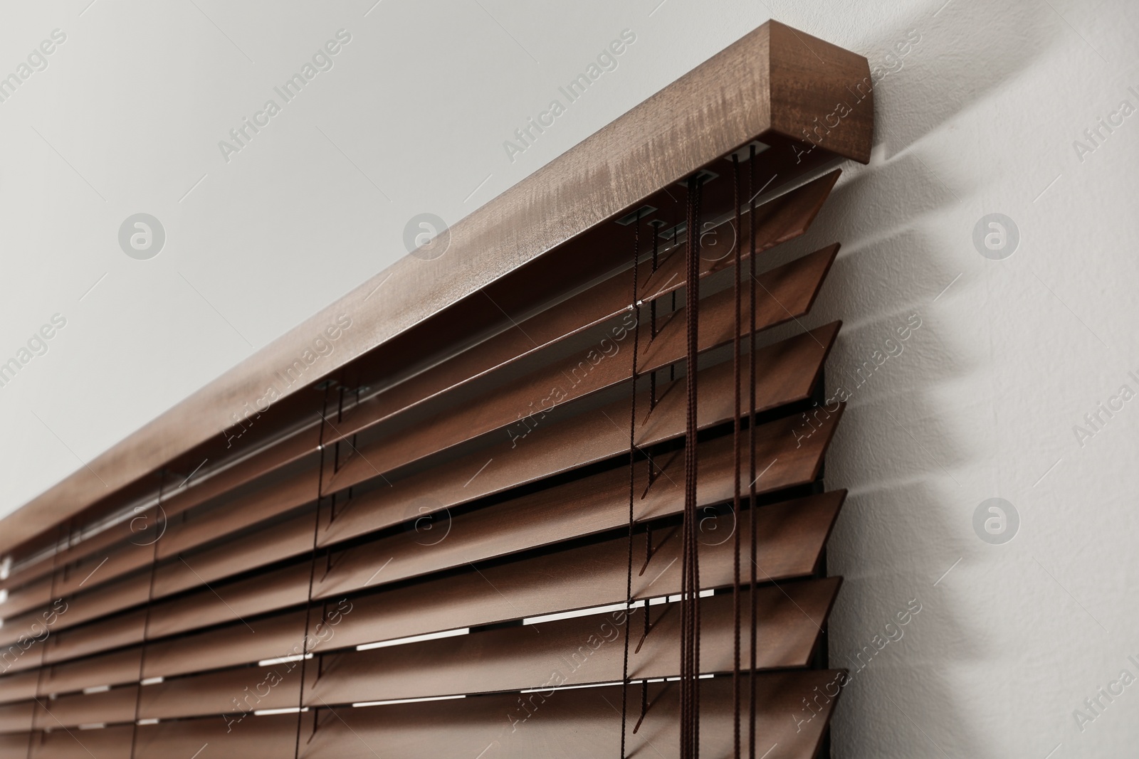 Photo of Modern window with closed stylish wooden blinds indoors, closeup view