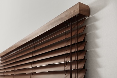 Photo of Modern window with closed stylish wooden blinds indoors, closeup view