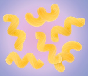 Image of Raw cavatappi pasta falling on color background