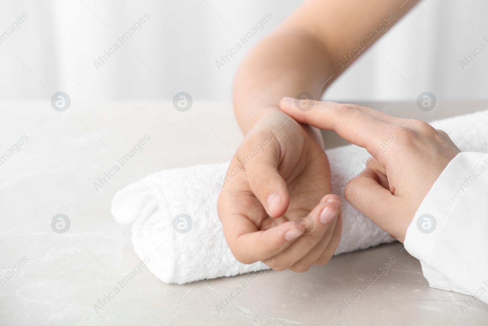 Photo of Doctor checking patient's pulse on table, closeup