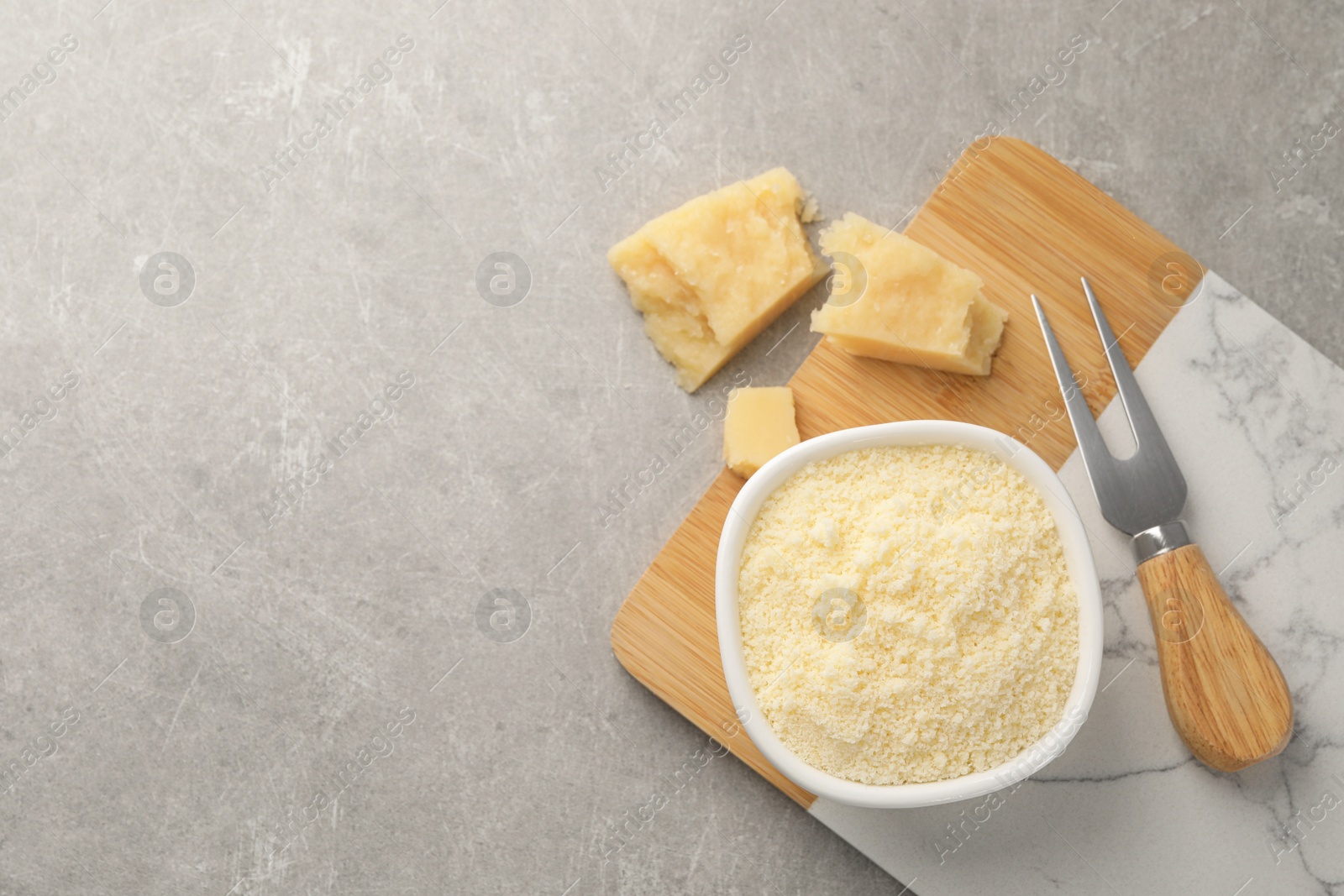 Photo of Parmesan cheese with fork on grey table, flat lay. Space for text