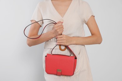 Photo of Woman with red stylish bag on light grey background, closeup