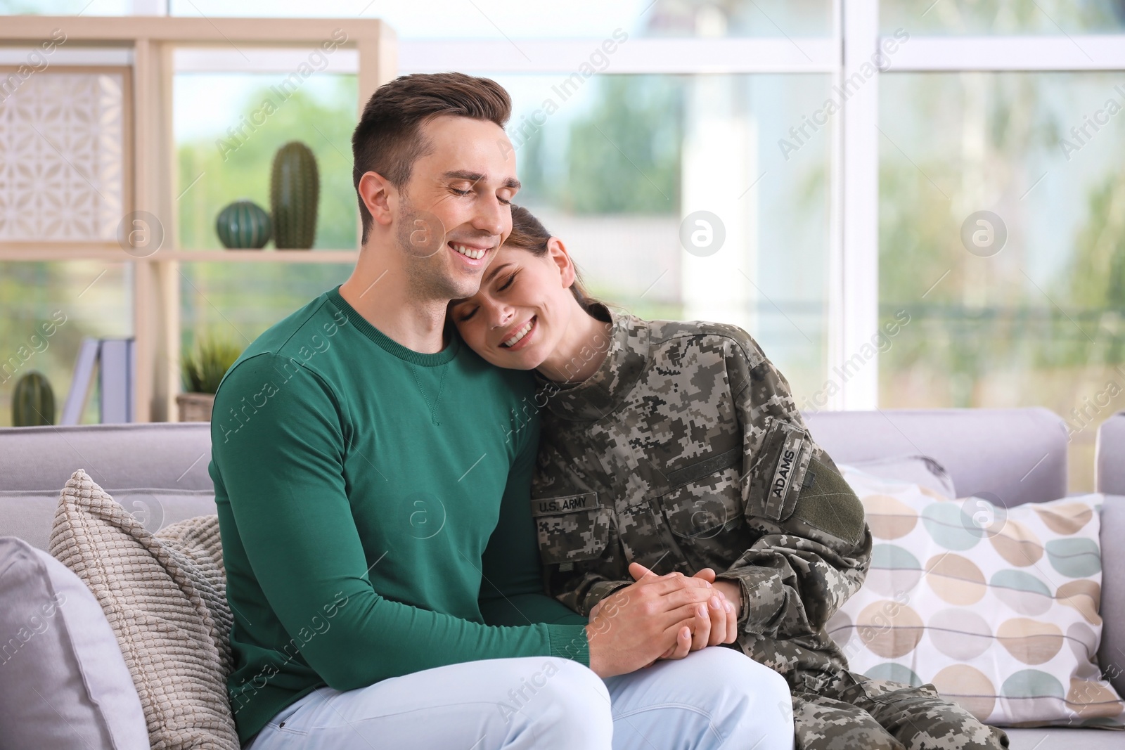 Photo of Woman in military uniform with her husband on sofa at home