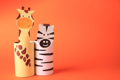 Photo of Toy giraffe and zebra made from toilet paper hubs on orange background, space for text. Children's handmade ideas