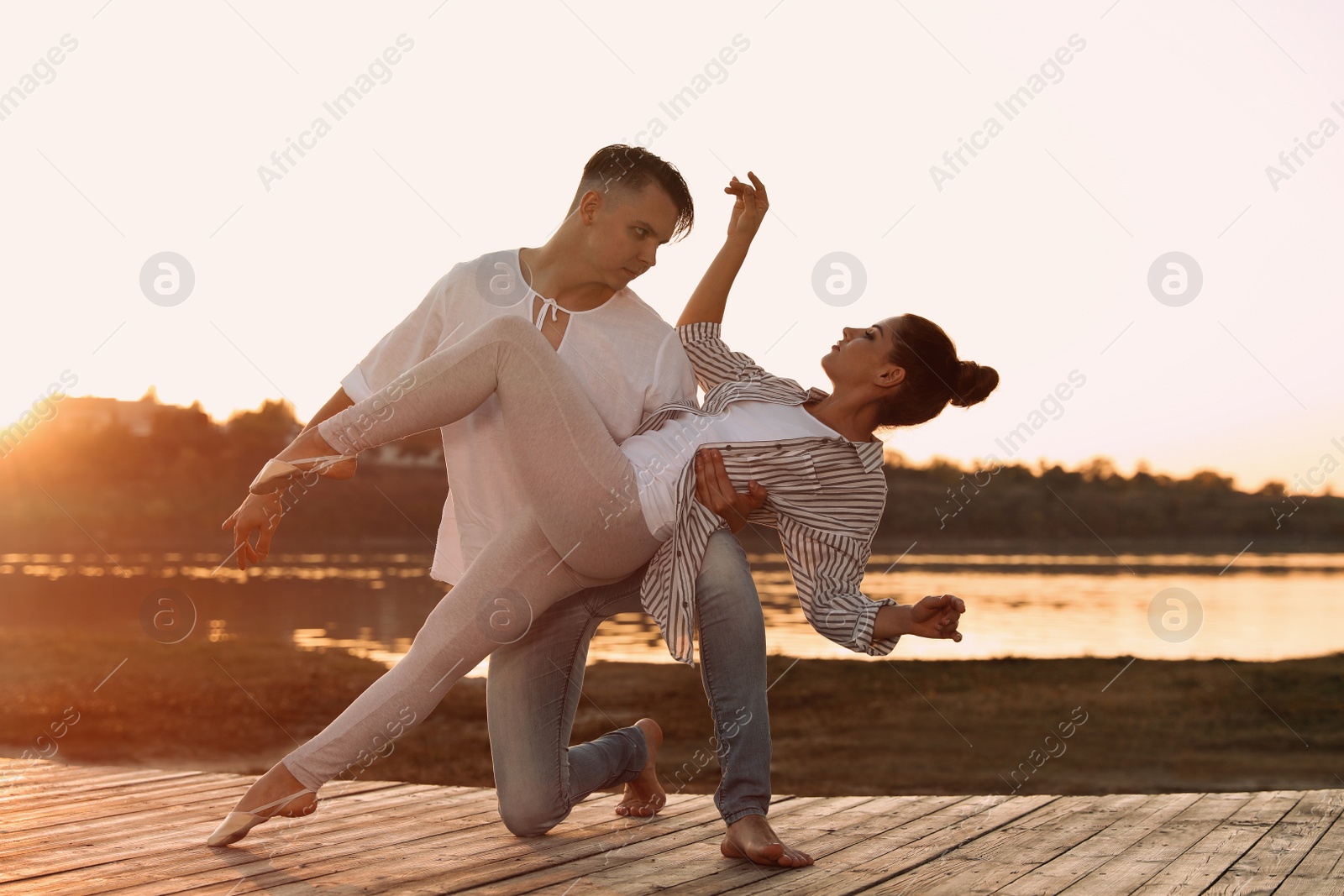 Photo of Beautiful young couple practicing dance moves near river at sunset