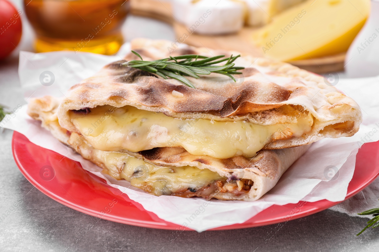 Photo of Tasty pizza calzones with cheese and rosemary on light grey table, closeup