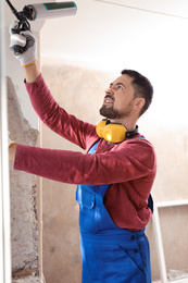 Worker using foam gun for window installation indoors