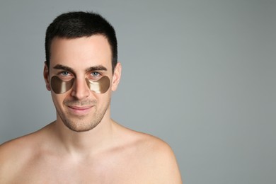 Photo of Young man with under eye patches on grey background. Space for text