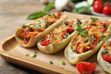 Photo of Delicious stuffed zucchini served on wooden table, closeup